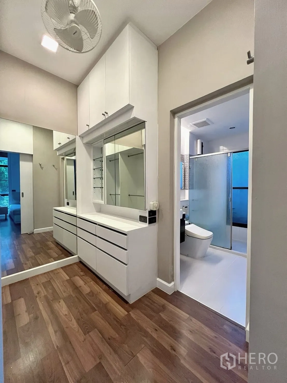 Detached House for rent in Prawet, Bangkok - Dressing area with built-in drawers, large mirror, and entry to a bathroom with glass shower.