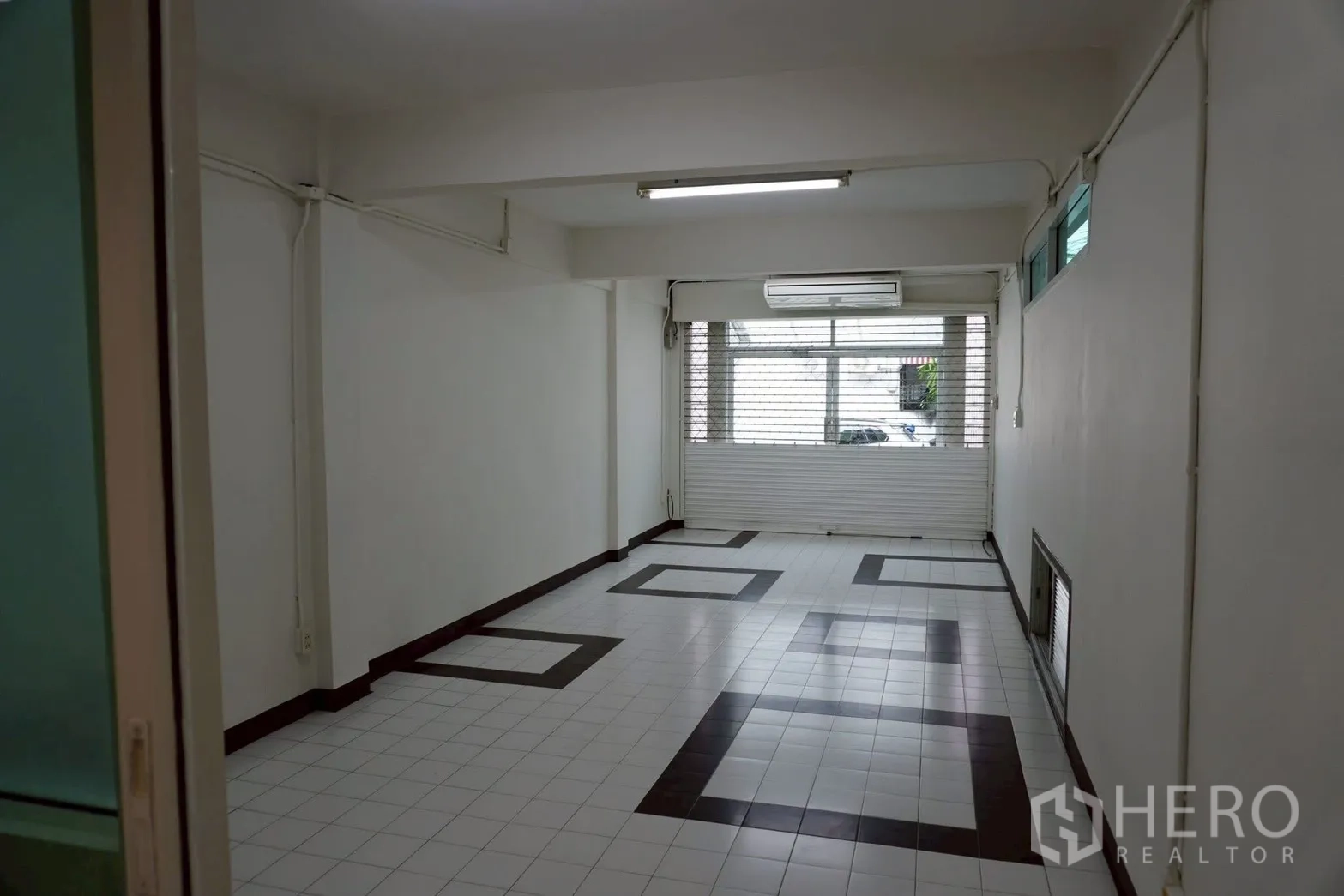 带办公室的家 for rent in Watthana, Bangkok - 一层接待大厅，几何地砖与卷闸门门面。