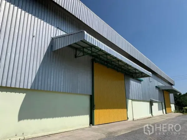 货栈 出租在Lat Krabang, Bangkok - 街侧视角的金属板仓库，超大黄色滑动门与遮阳雨棚。