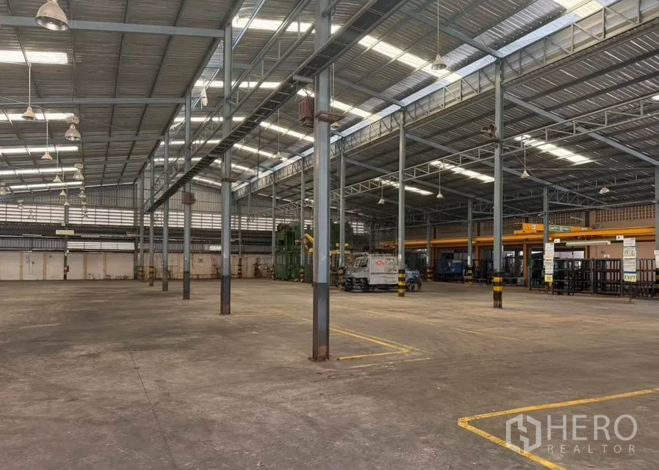 Factory for rent in Bang Phli, Samut Prakan - Large production floor with metal pillars, overhead lighting and painted safety lanes.