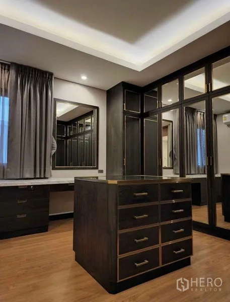 Townhouse for sale in Yan Nawa, Bangkok - Walk-in closet with island dresser, mirrored wardrobes and soft ambient lighting.