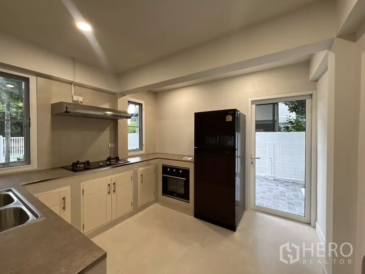 Detached House for rent in Saphan Sung, Bangkok - Fitted kitchen with gas hob, oven, fridge and door to the side yard.