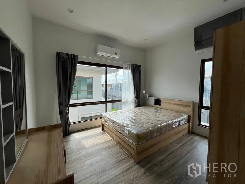 Detached House for rent in Bang Kapi, Bangkok - Bright secondary bedroom with large corner windows, bed and air conditioning.