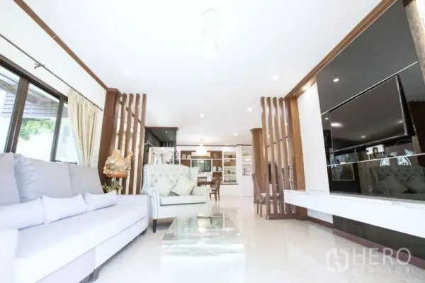 Detached House for sale in Lat Krabang, Bangkok - Open-plan lounge with built-in TV wall, wood accents and view toward dining and kitchen.