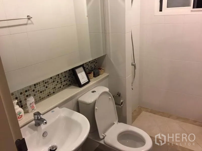 Detached House for rent or sale in Khlong Toei, Bangkok - Bright bathroom with vanity sink, toilet, mosaic backsplash and walk-in shower zone.