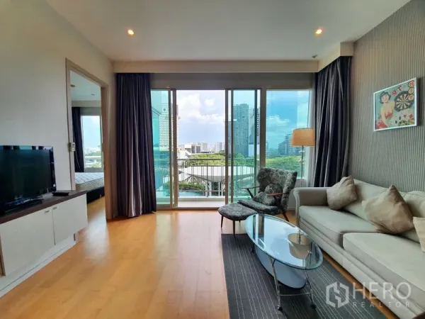 Condominium for rent in Chatuchak, Bangkok - Living area facing large sliding glass doors to a balcony with city views and a doorway to the bedroom.