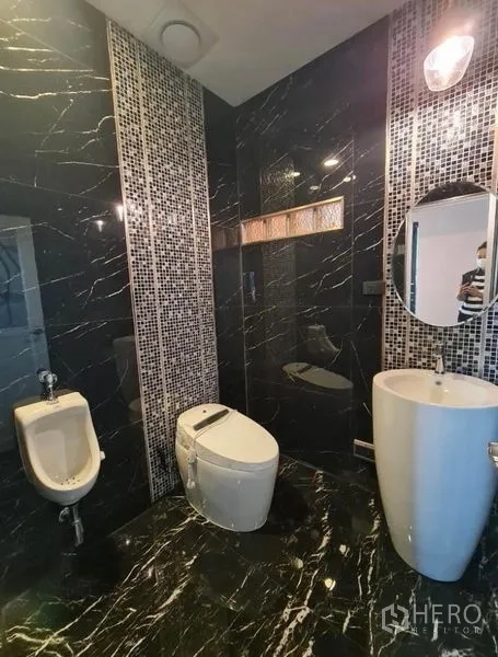 Detached House for sale in Sai Mai, Bangkok - Stylish bathroom with black marble tiles, pedestal sink, toilet, and urinal.