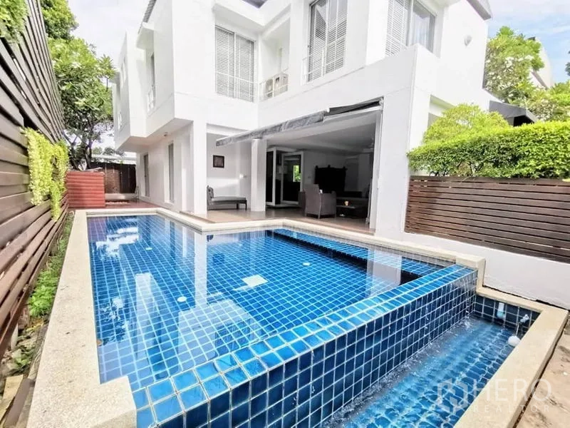 Detached House for rent or sale in Bang Phli, Samut Prakan - Private blue-tiled swimming pool beside white two-storey home and timber privacy screen.