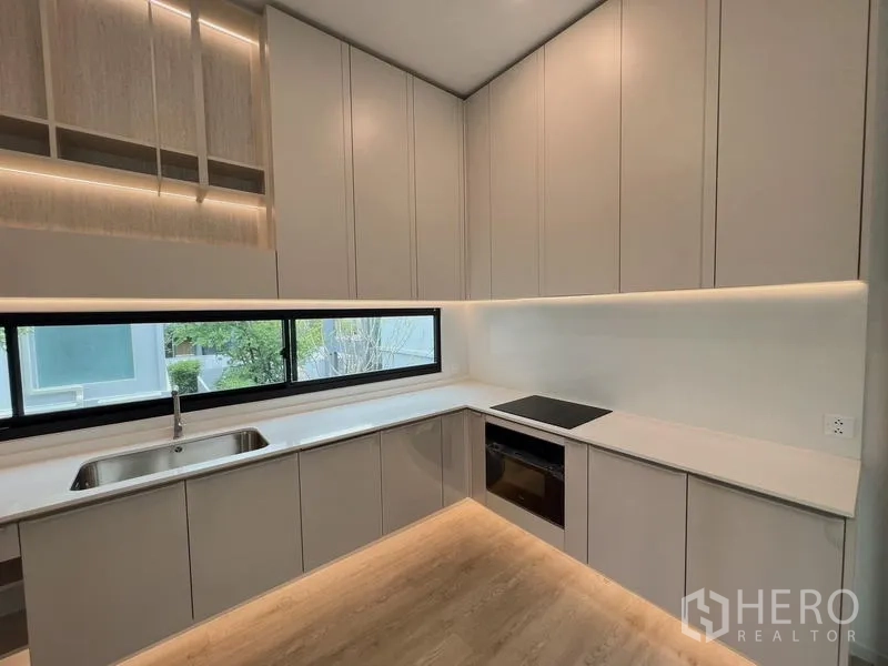 Detached House for rent or sale in Saphan Sung, Bangkok - Full kitchen with built-in oven, electric cooktop, and long horizontal window.