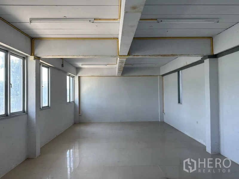 Factory for rent in Lam Luk Ka, Pathum Thani - Large office workspace with windows on two sides and glossy tile flooring.