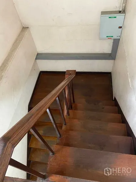 Retail Space for rent in Bang Rak, Bangkok - View down a wooden staircase with handrail and an electrical panel mounted on the wall.