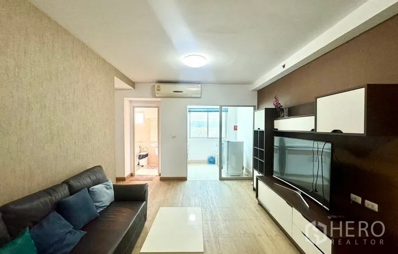 公寓 出租在Huai Khwang, Bangkok - 客厅带内置电视柜，推拉玻璃门通往阳台和洗衣区。