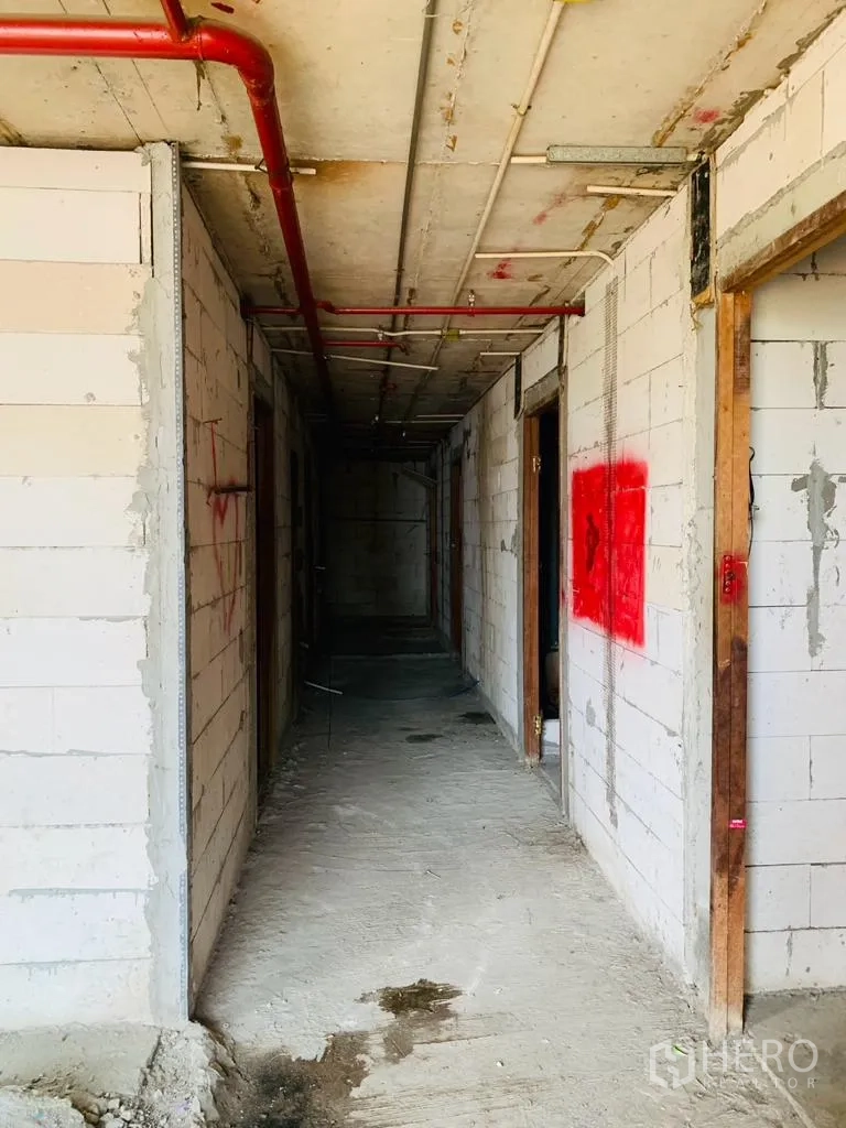 带办公室的家 出租 - 在建的长走廊，红色喷淋管与砌块墙体。