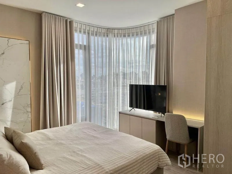Condominium for rent in Watthana, Bangkok - Bedroom with curved window, city view, TV cabinet and built‑in study desk.