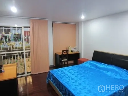 带办公室的家 出租或出售在Wang Thonglang, Bangkok - 卧室配大床、书桌，推拉门通向阳台。