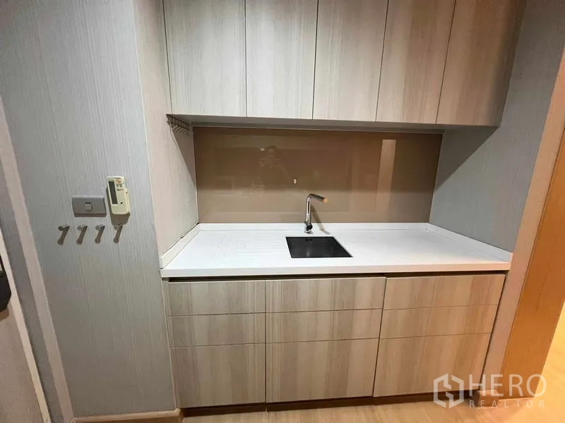 Condominium for rent or sale - Opposite kitchen counter with sink, backsplash, and upper and lower cabinets.