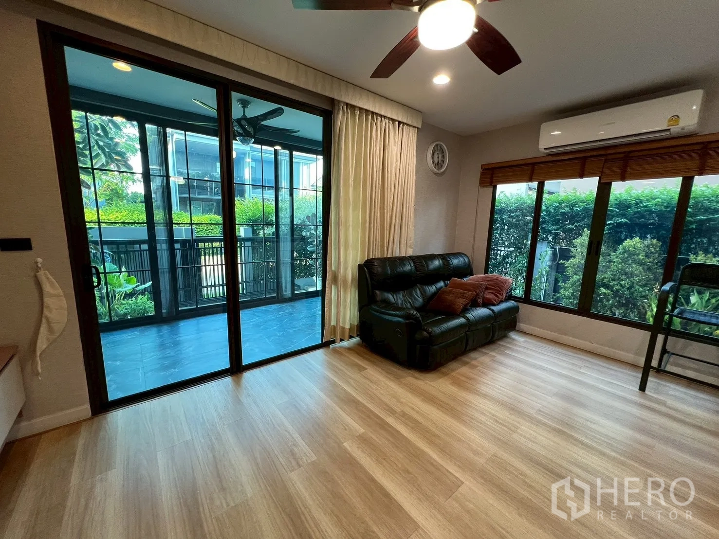 Detached House for rent in Bang Kapi, Bangkok - Living area with sliding glass doors opening to covered terrace and garden hedge.