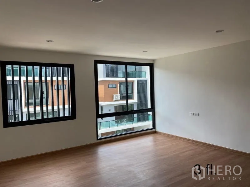 Home Office for rent or sale in Bang Phli, Samut Prakan - Corner bedroom or meeting room with big windows and wood floors, view to neighboring buildings.
