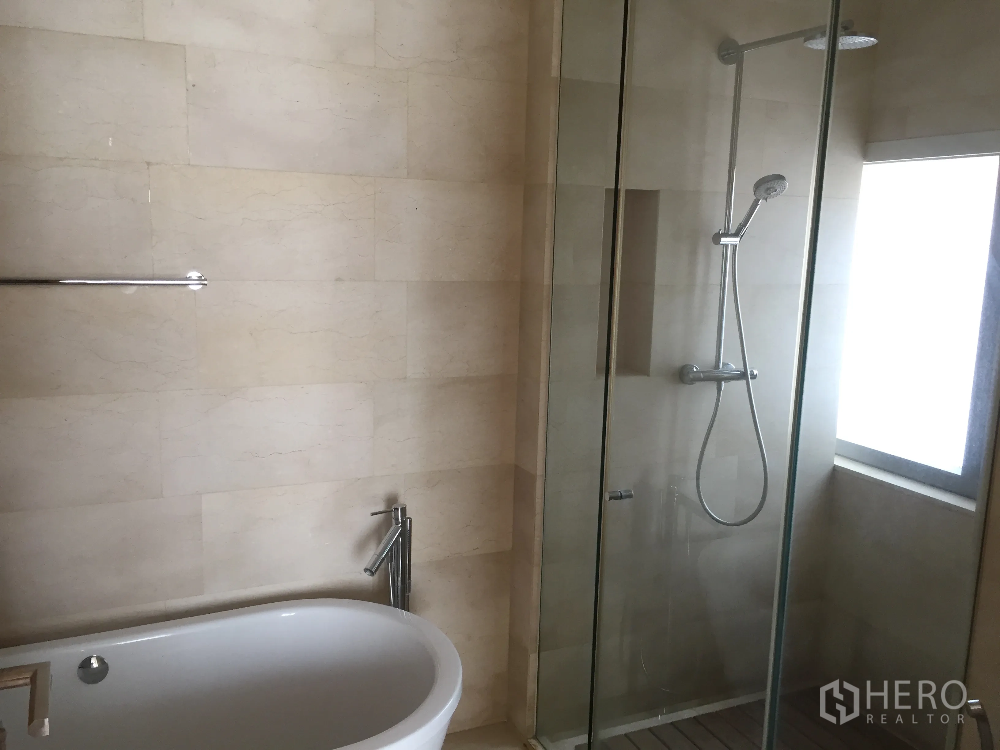 Condominium for rent in Bang Rak, Bangkok - Modern bathroom with glass-enclosed shower and freestanding bathtub in stone tile finish.