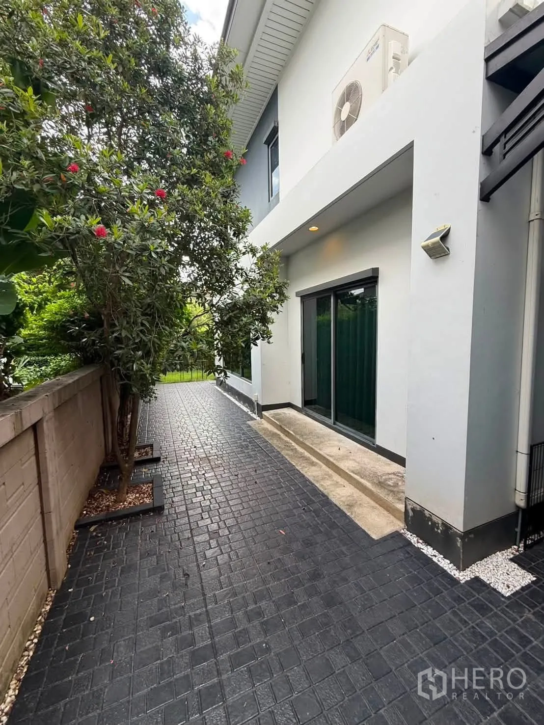 Detached House for rent in Bang Kapi, Bangkok - Open side yard with a tree, sliding glass door, and paved terrace.