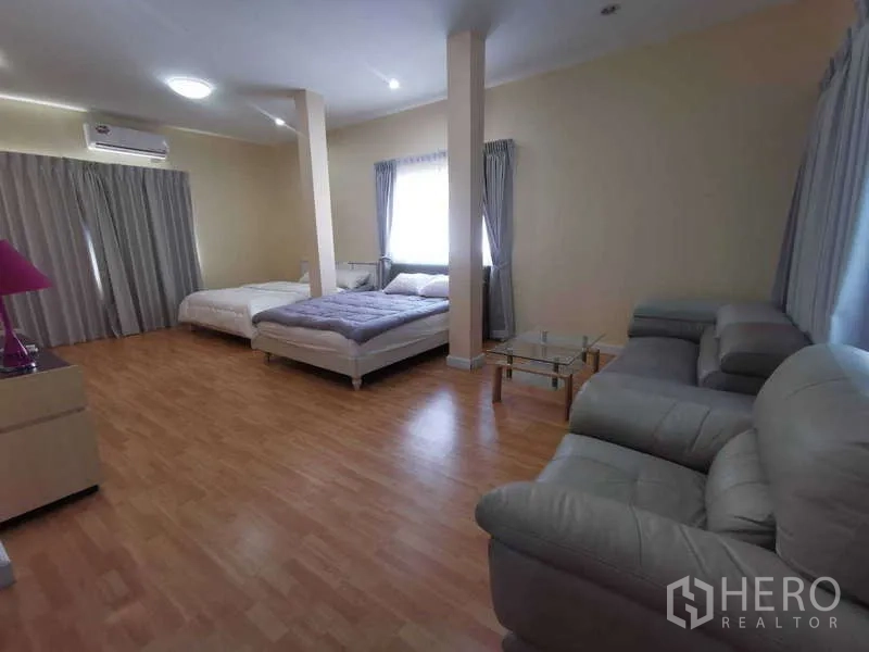 Townhouse for rent in Chatuchak, Bangkok - Oversized bedroom with two beds, sofa seating and laminate floors.