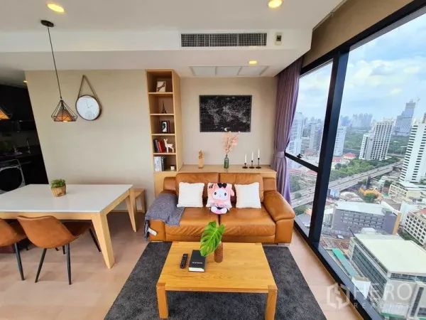 Condominium for rent in Bang Rak, Bangkok - Cozy lounge with built-in shelves, leather sofa and corner glazing facing the city.