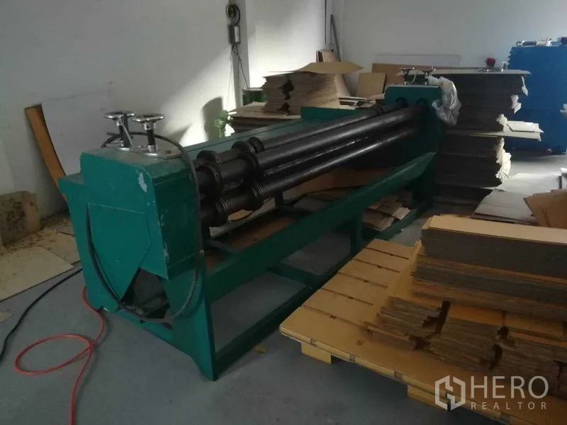 工厂 for sale in Bang Len, Nakhon Pathom - 绿色滚筒设备与堆放的裁切纸板位于车间内。