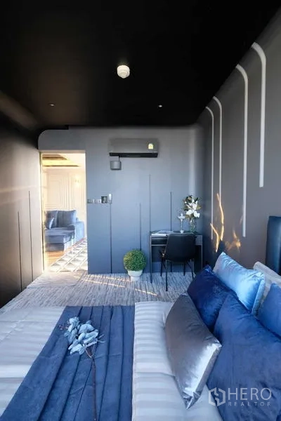 Condominium for sale - Compact bedroom with blue headboard and ambient wall lighting.