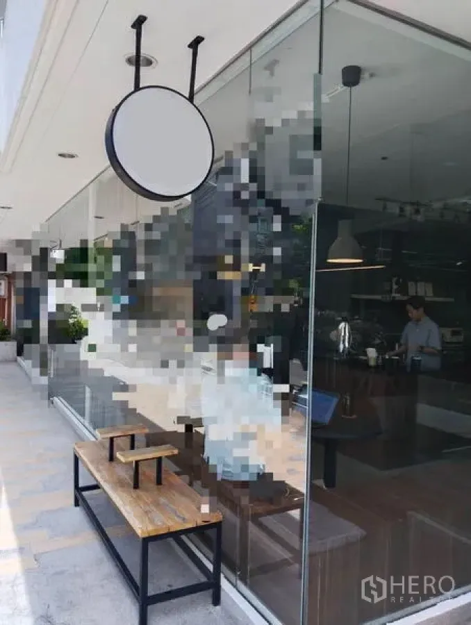 พื้นที่ขายปลีก ให้เช่าในWatthana, Bangkok - หน้าร้านกระจกติดถนน พร้อมป้ายกลมแขวนและม้านั่งไม้ริมทางเดิน