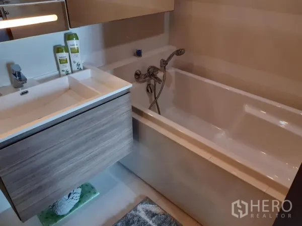 Condominium for rent in Khlong Toei, Bangkok - Bathroom area with full-size bathtub and wall-mounted vanity with storage.