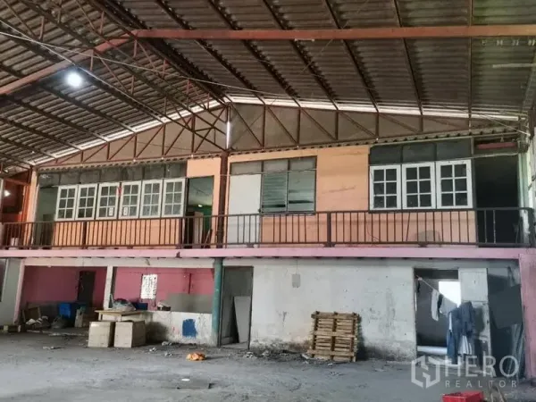 Warehouse for rent in Lam Luk Ka, Pathum Thani - Close view of mezzanine office rooms and railings beneath a steel truss roof inside the warehouse.