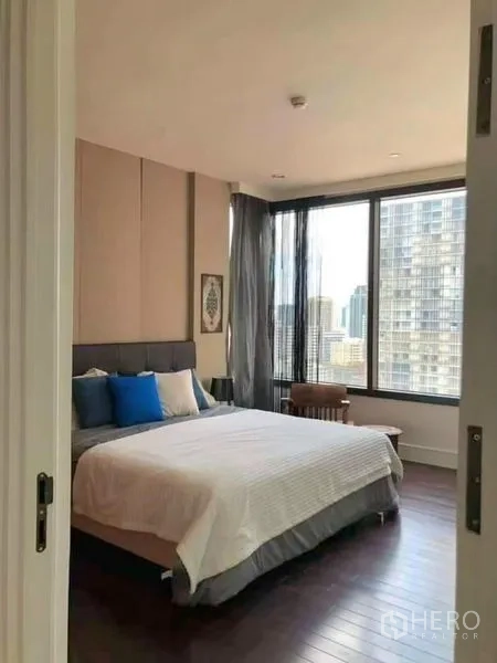 Condominium for rent in Khlong Toei, Bangkok - Bright master bedroom with large windows, city views, wood floors and a queen bed.