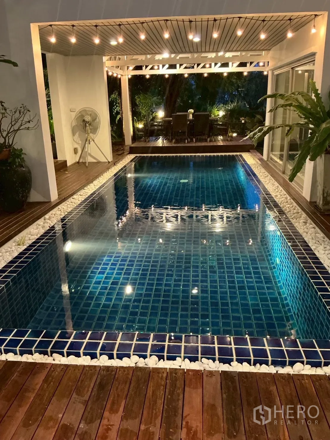 独栋房屋 for sale in Suan Luang, Bangkok - 蓝色马赛克游泳池，木质平台与夜间串灯。