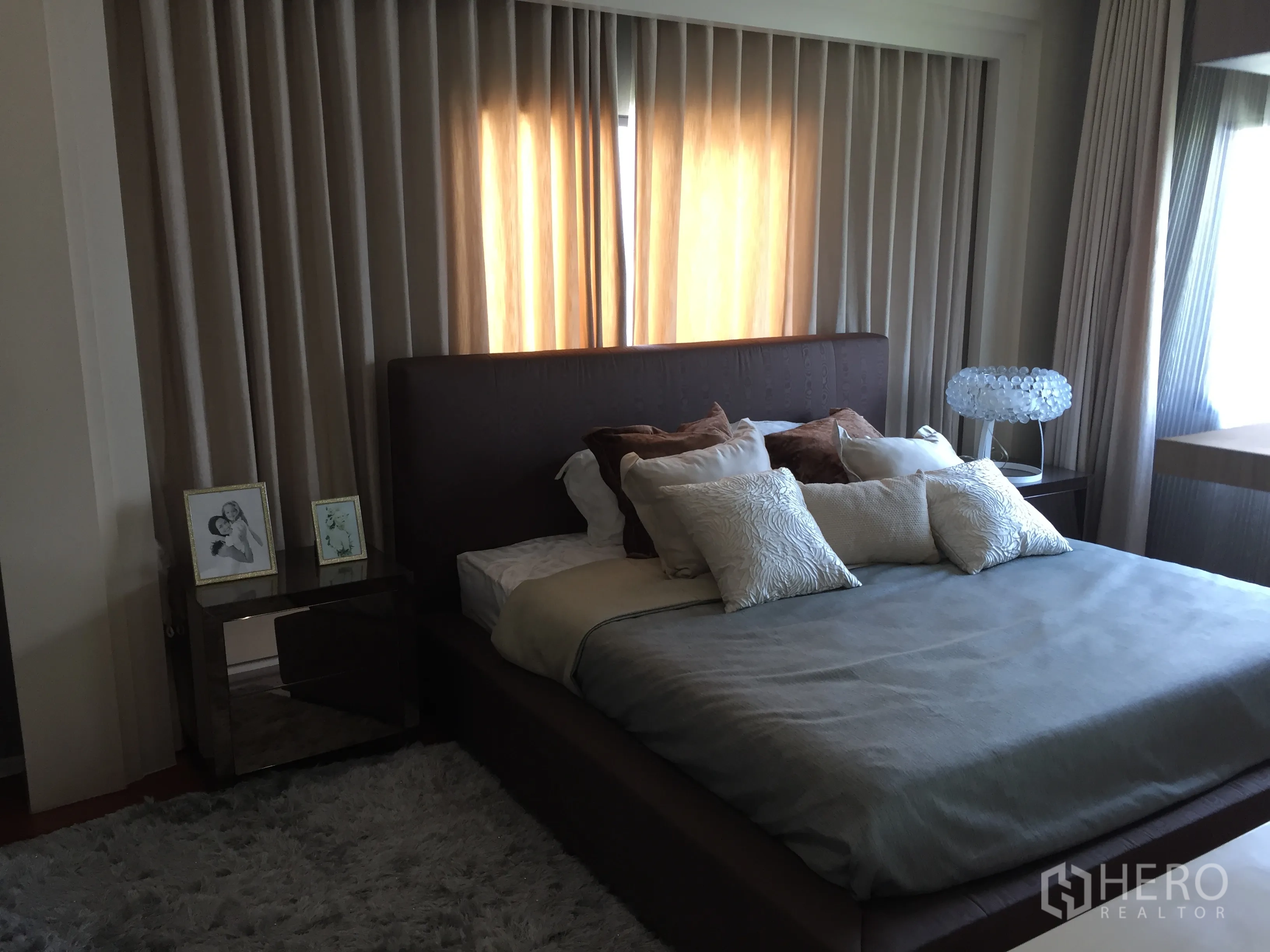 Detached House for sale in Prawet, Bangkok - Guest bedroom with upholstered bed, layered curtains and soft rug.