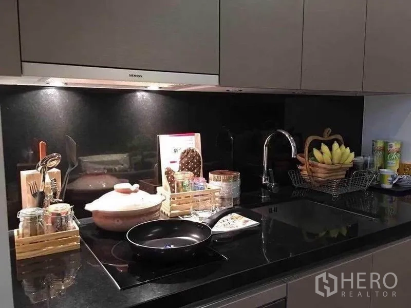 Condominium for rent in Watthana, Bangkok - Close-up of a sleek kitchen counter with induction cooktop, sink, and storage.