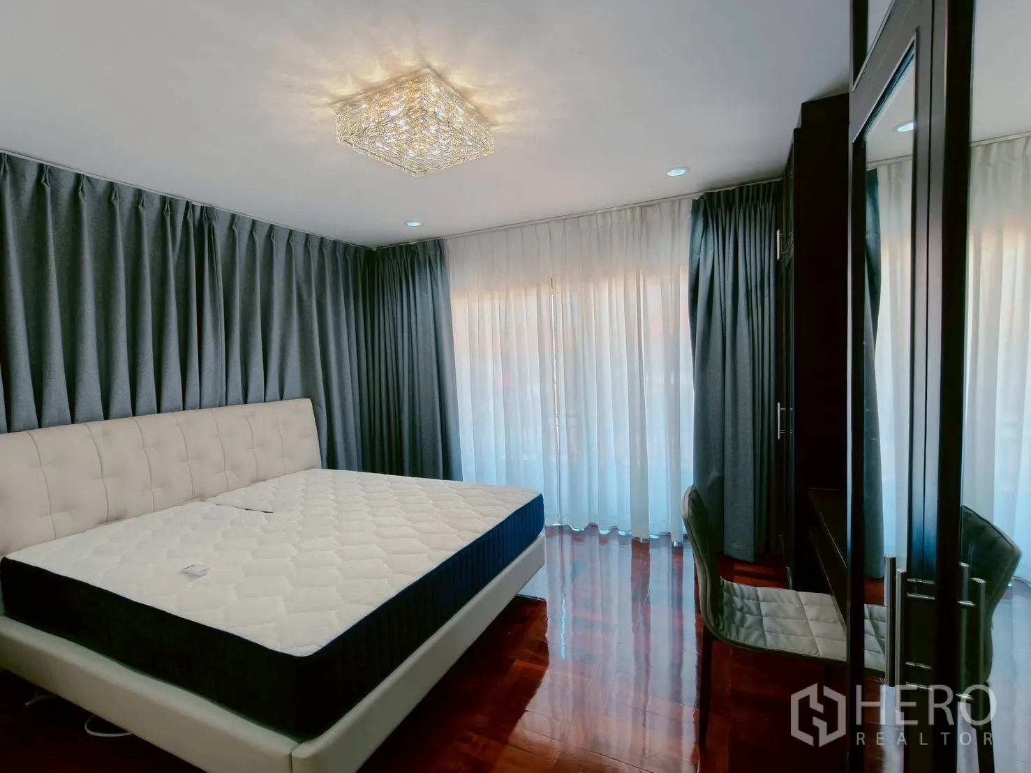 Detached House for rent in Lat Krabang, Bangkok - Master bedroom with upholstered king bed, full-length curtains, wardrobe and vanity.