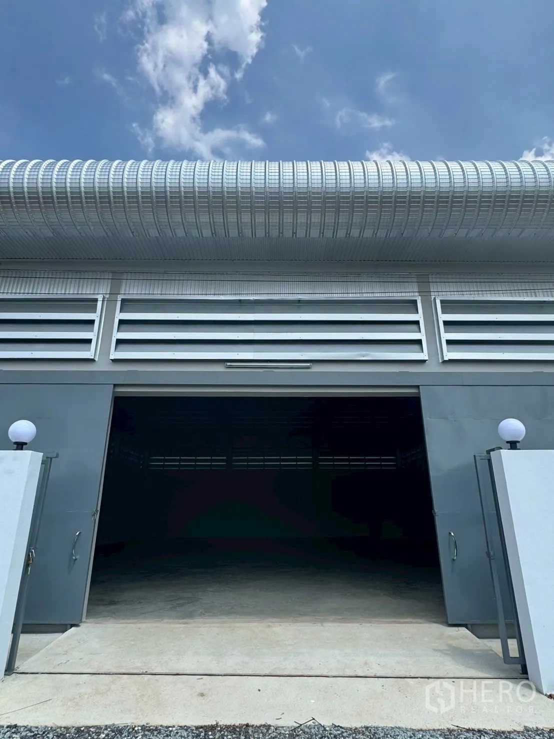 Warehouse for rent or sale in Nong Chok, Bangkok - Front view of warehouse with wide sliding steel door open and concrete driveway for easy truck access.