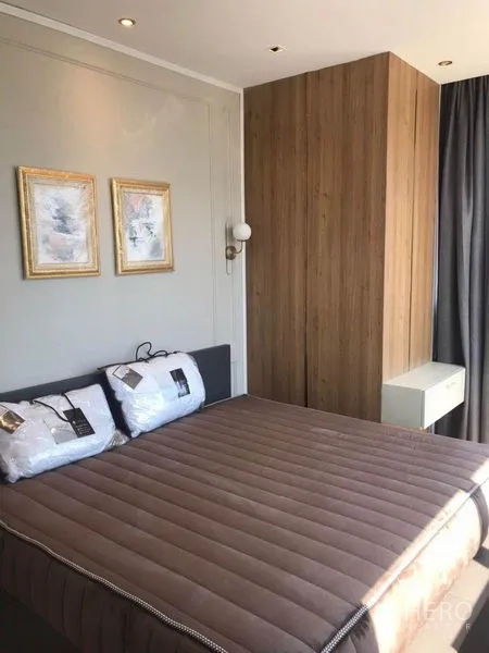 公寓 出租在Bang Rak, Bangkok - 明亮卧室，木质装饰墙、壁灯与挂画点缀。