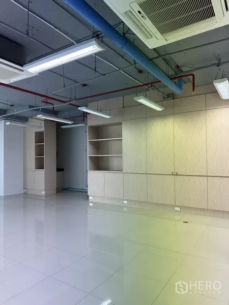 Office Space for rent in Khlong Toei, Bangkok - Built-in light wood storage cabinets and shelving along the wall under an exposed ceiling in a modern office.