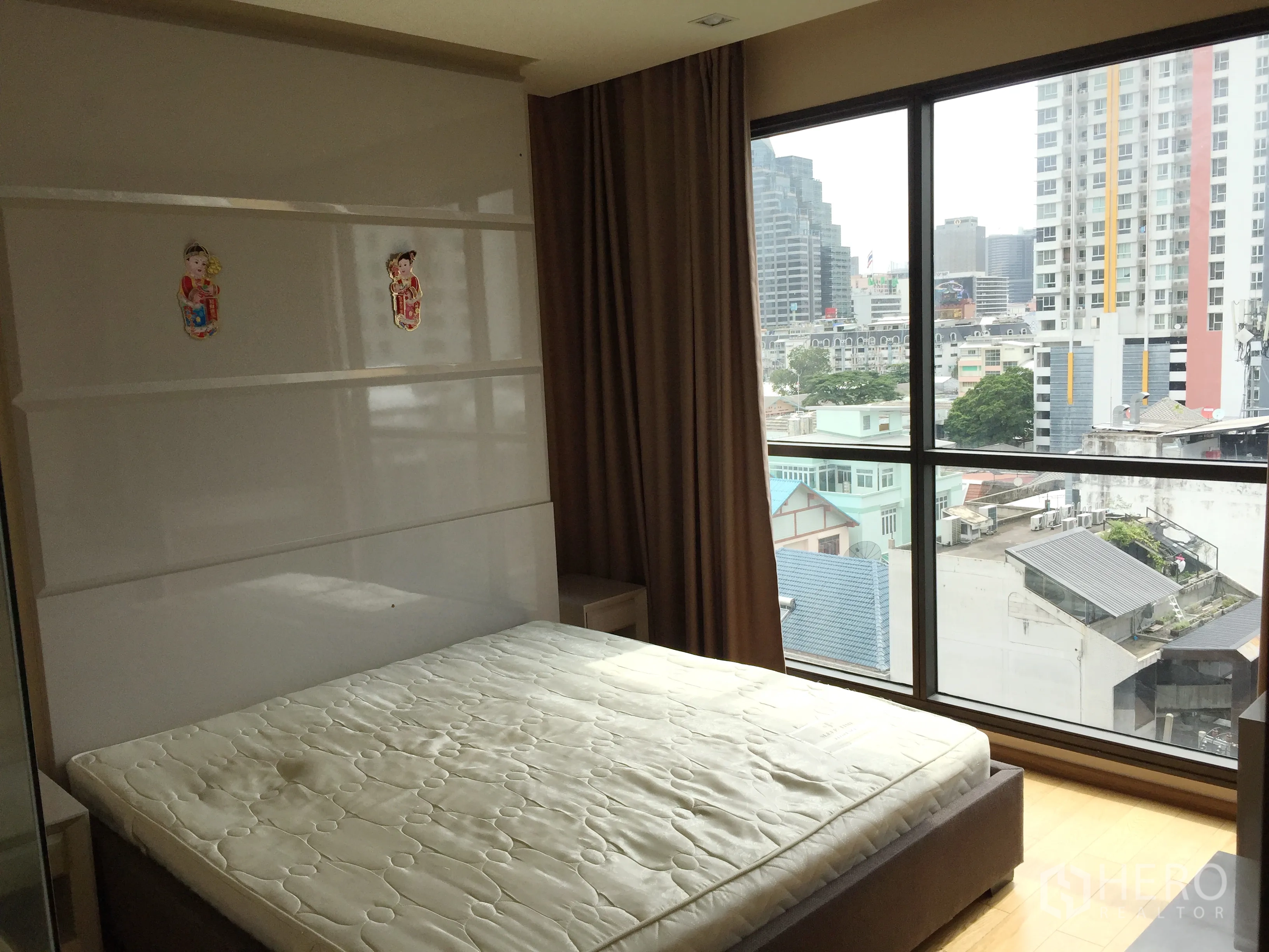 Condominium for rent in Bang Rak, Bangkok - Master bedroom with large windows showcasing a city skyline view.