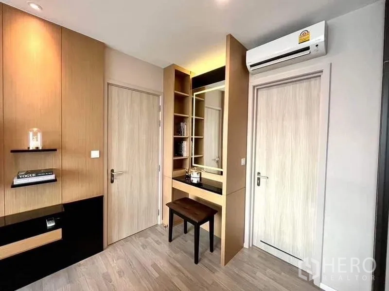 Condominium for sale in Bang Sue, Bangkok - Corner dressing area with shelving, illuminated mirror, two wooden doors and wall-mounted air conditioner.
