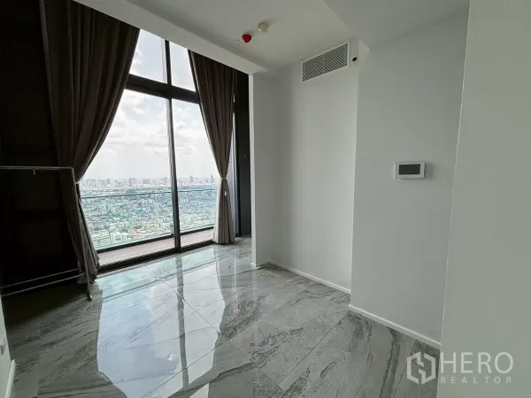 公寓 出售在Bang Kho Laem, Bangkok - 高楼层起居区，落地窗与灰色大理石地面，西向城市天际线景观与窗帘。