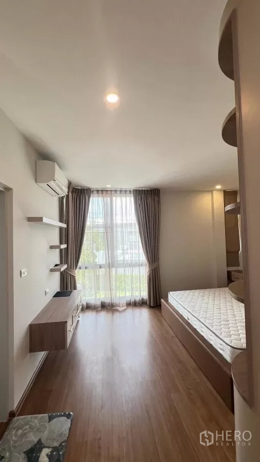 Townhouse for rent in Bang Phli, Samut Prakan - Primary bedroom with large window, curtains, built-in desk and air conditioner.