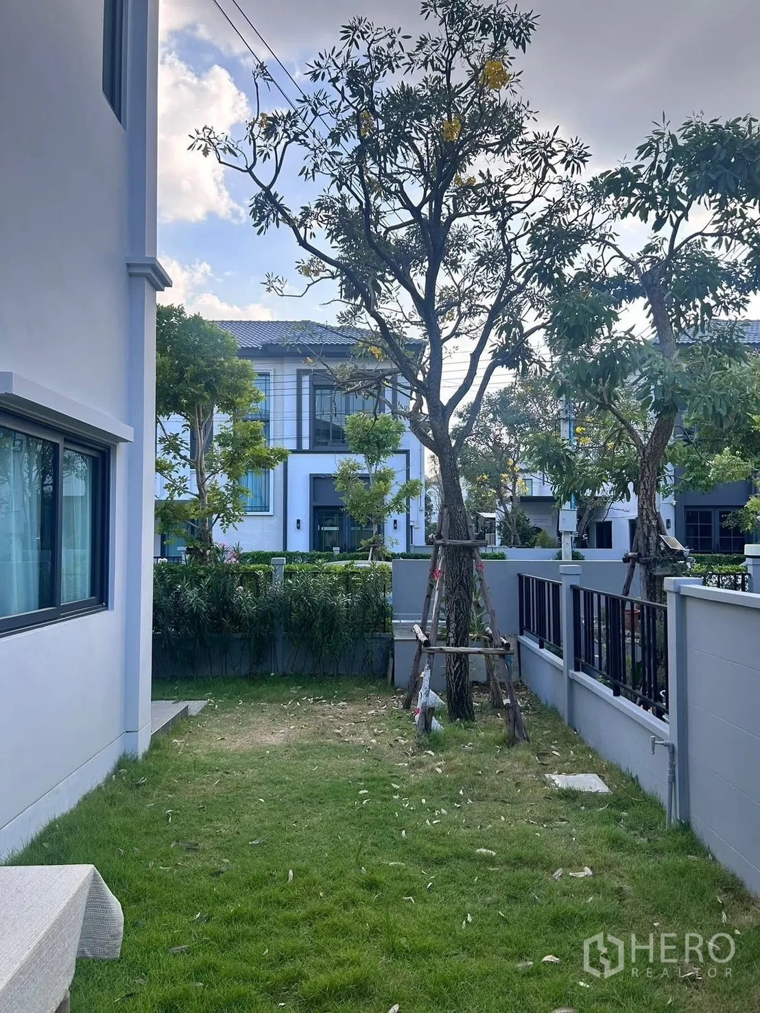Semi-detached House for rent in Bang Phli, Samut Prakan - Private grassy backyard with trees and perimeter fence.