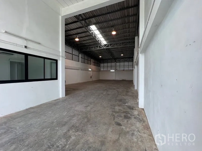 货栈 出租在Bang Phli, Samut Prakan - 高挑仓库大厅，钢桁架屋顶、天窗与混凝土地面。