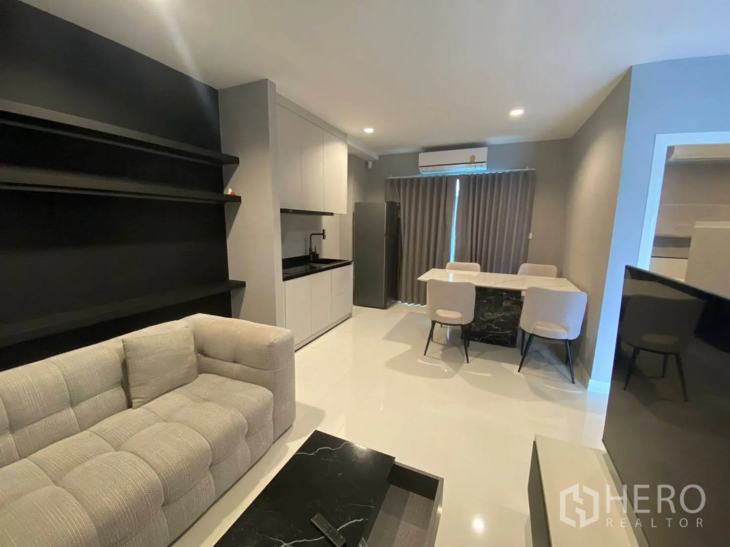 Townhouse for rent in Bang Kapi, Bangkok - Living and dining area with built-in shelving, compact kitchen, dining table, and curtains.