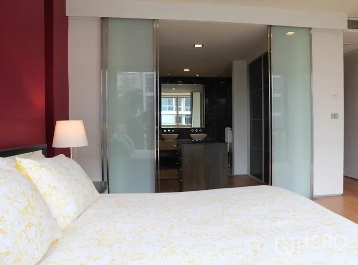 Condominium for rent in Khlong Toei, Bangkok - Master bedroom view to the ensuite bathroom through frosted sliding glass doors.