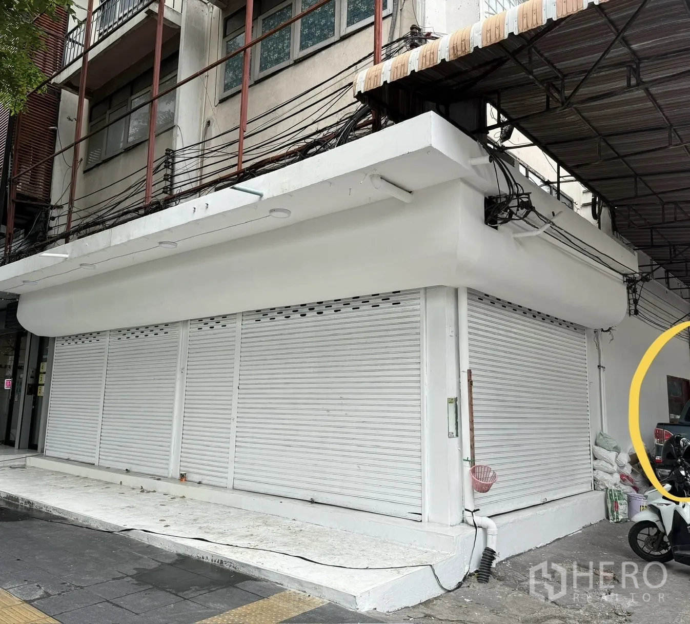 Shophouse for rent in Khlong Toei, Bangkok - Corner exterior with freshly painted white shutters and sidewalk frontage.