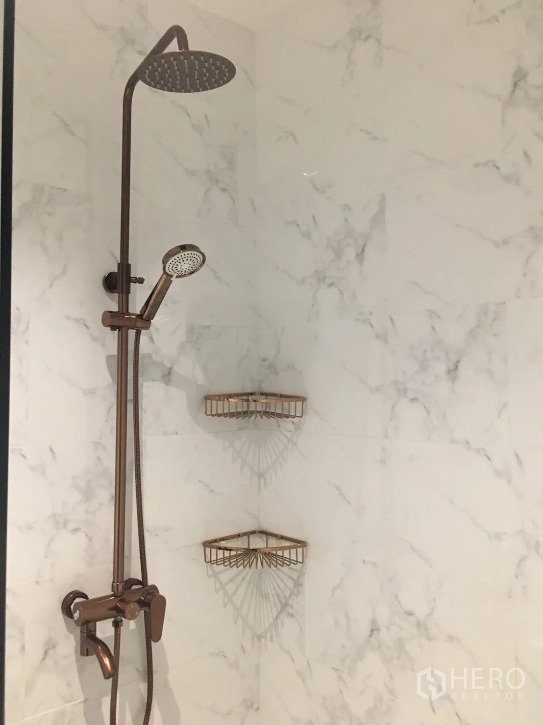 Condominium for rent in Khlong Toei, Bangkok - Marble-tiled shower with rainfall head, handheld sprayer and bronze fittings.