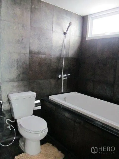 Condominium for rent in Khlong Toei, Bangkok - Bathroom with a built-in bathtub, handheld shower, and a small window for ventilation.